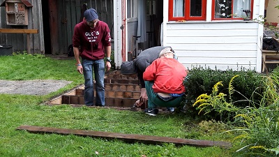 Drei Freiwillige tauschen die Latten der Terrasse aus.