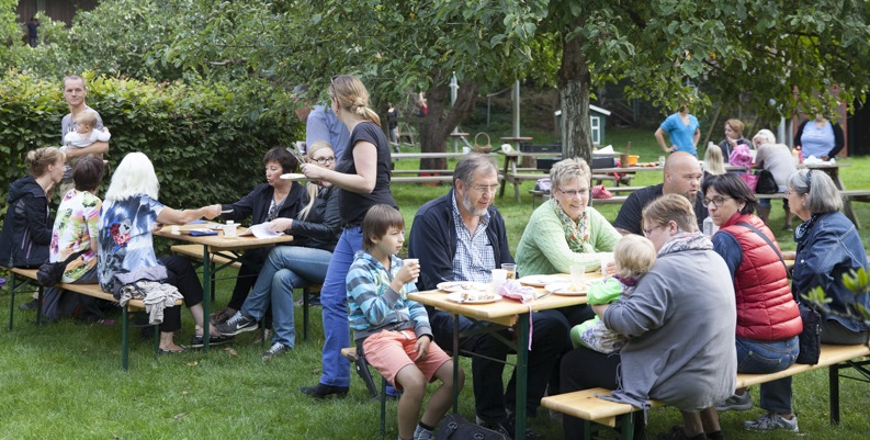 Eltern und Leihgroßeltern essen zusammen im Grünen.