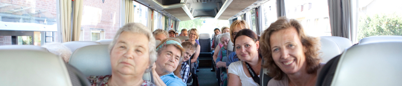 Senioren und Freiwillige sitzen im Bus