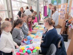 Kinder versammeln sich vor Schülern um einen Tisch