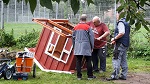 Handwerker und Freiwillige arbeiten am Unterbau eines Holz-Spielhauses für Kinder.