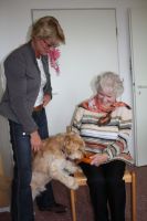 Eine Frau besucht mit ihrem Hund eine ältere Dame