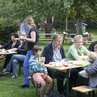 Eltern und Leihgroßeltern essen zusammen im Grünen.